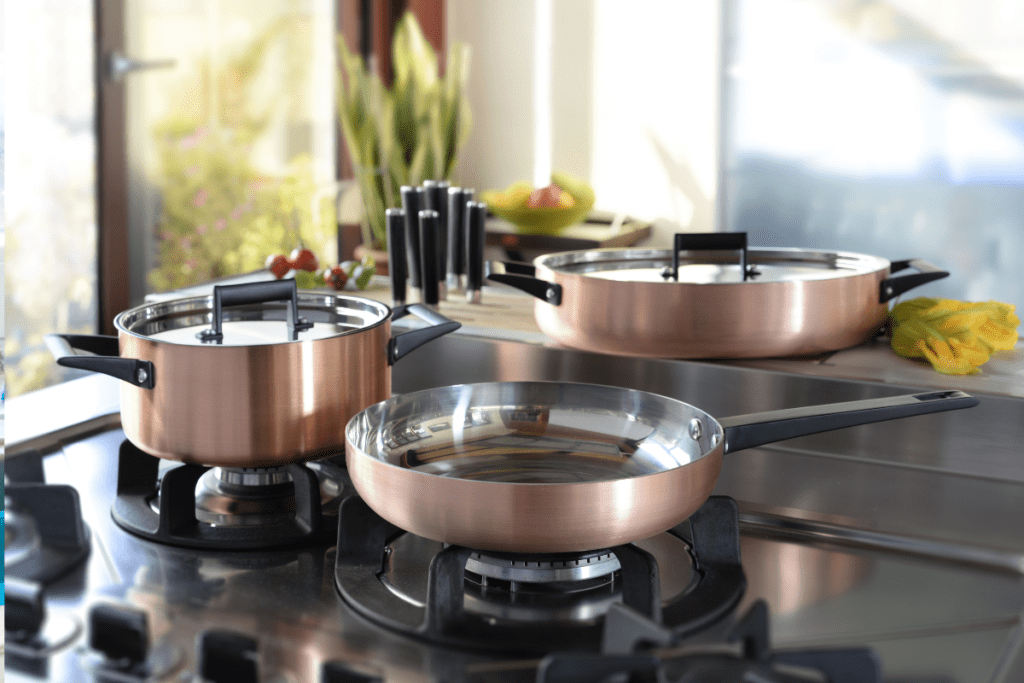 A pot and a sauce pan sit on a gas stove, and another pot sits off the burner.