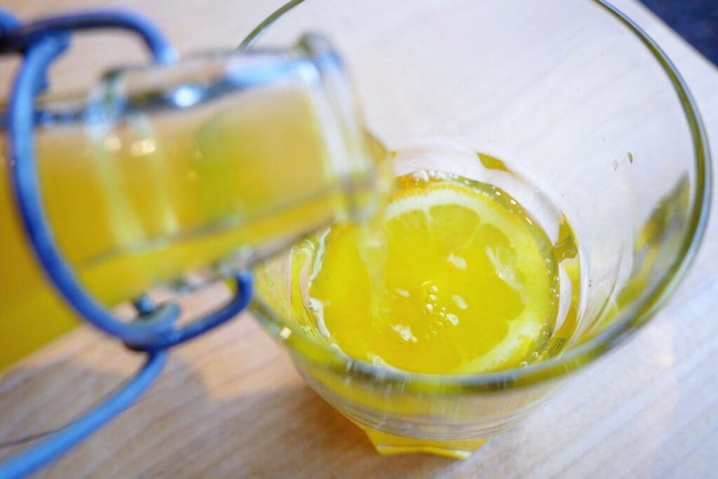 Turmeric Cardamom Fizz made with ginger bug poured into a glass with a lemon at the bottom.