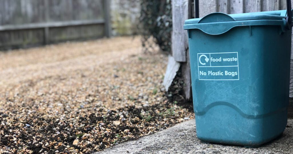 A blue compost bin sits in the driveway.