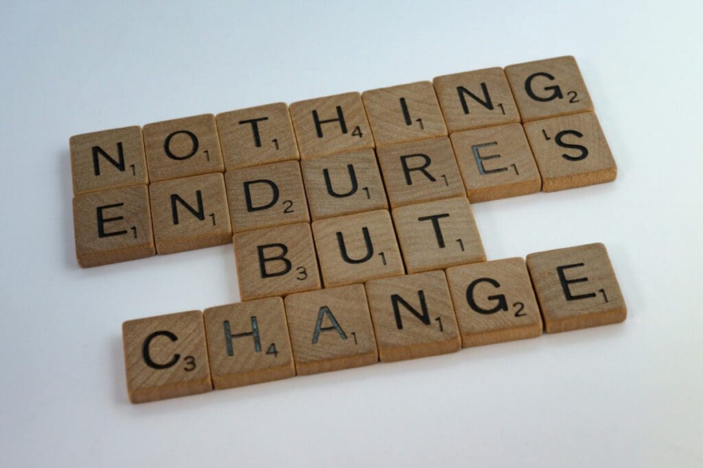 Wooden letter tiles arranged to spell "NOTHING ENDURES BUT CHANGE" on a white background.