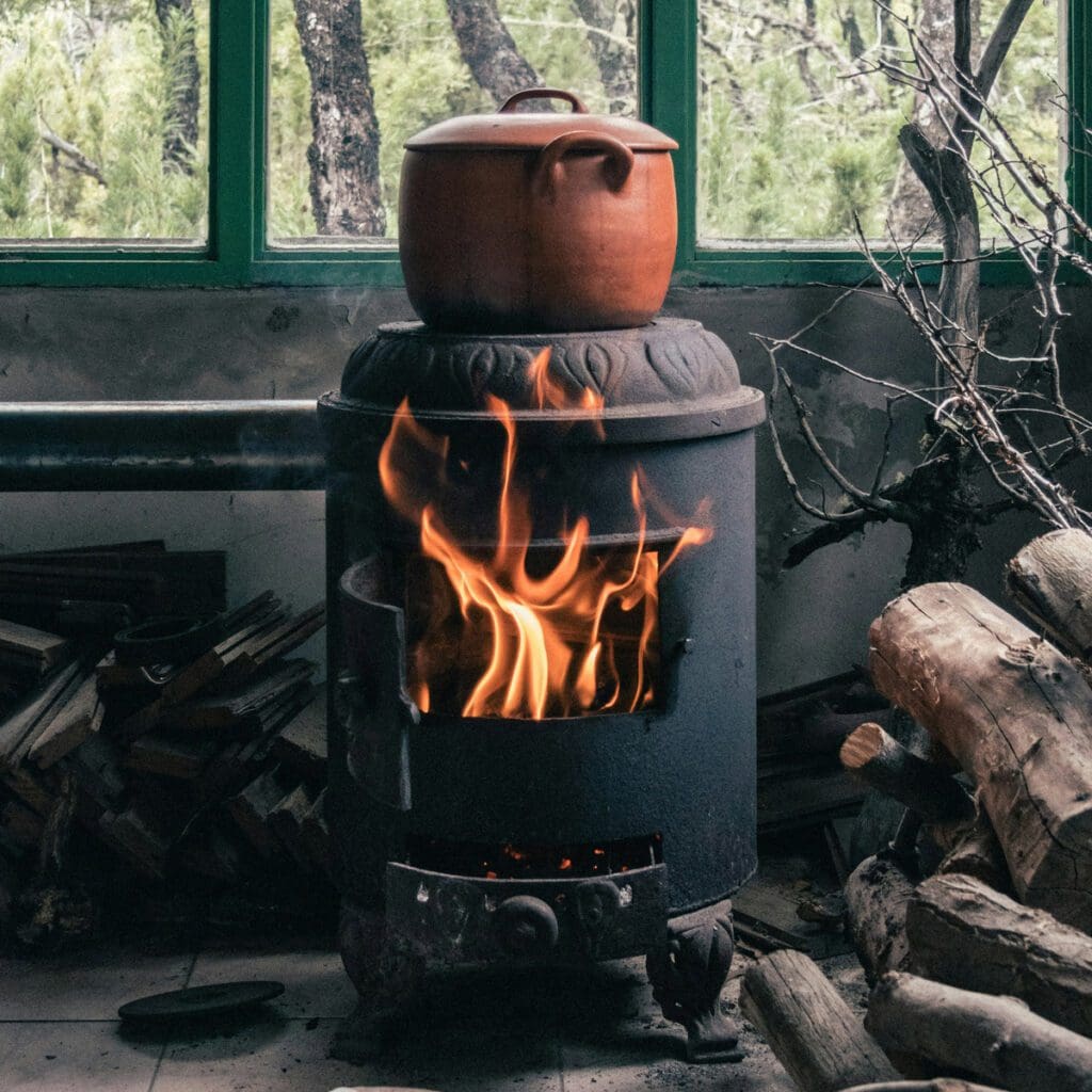 A large pot sits heating on a wood stove.