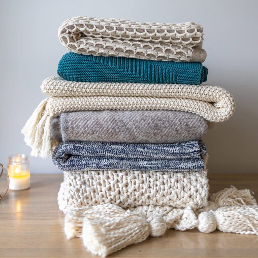 A stack of folded multi-colored throw blankets sits on the floor.