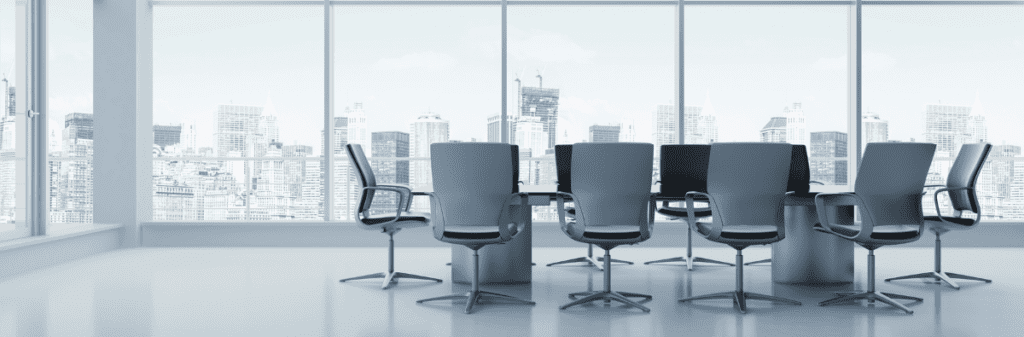 Empty office space in a high rise building with large windows featuring a large conference table.