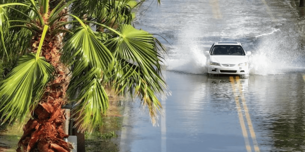 A car drives cautiously through a flooded road in the aftermath of Hurricane Helene