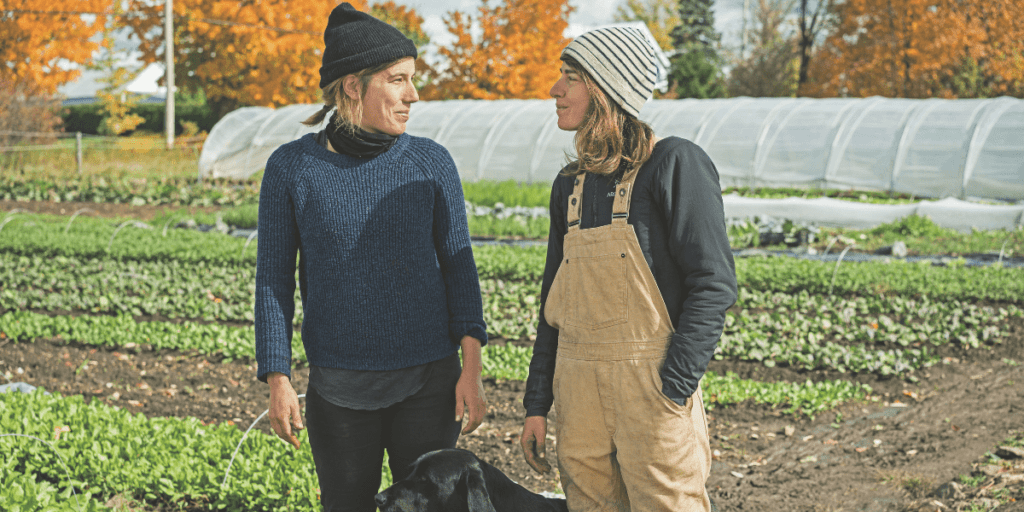 Two people in a field with vibrant fall foliage, wearing beanies and chatting about essential lessons they've learned, with their dog playfully nearby. The serene scene captures the spirit of better management in all aspects of life.