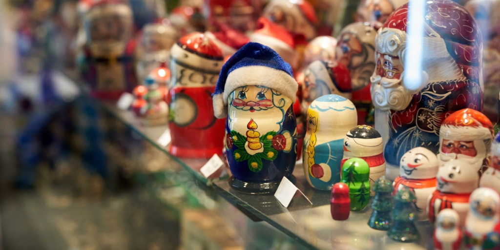 Colorful nesting dolls in festive attire, displayed on a shelf, make for thoughtful gifts that embody the spirit of conscious gifting.