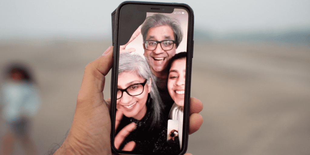 A hand holding a phone depicts a video call with three smiling people, showcasing the power of technology and its ability to foster connection. Yet, it's important to know when not to use it, honoring moments that deserve our undivided attention away from screens.