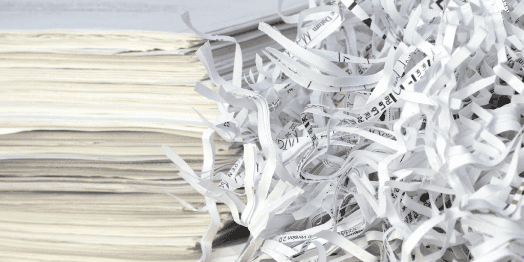 A stack of papers sits neatly beside shredded strips, representing a new wave of sustainable practices embraced by publishers in Frankfurt.