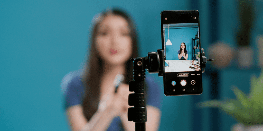 How to support local creators without spending money: capture engaging content by recording a video with your smartphone on a tripod against a blue background.