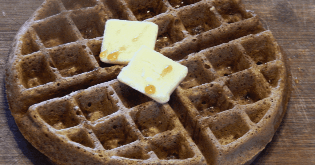 A holiday zucchini waffle topped with two melting butter slices and drizzled with syrup invites you to savor every bite.