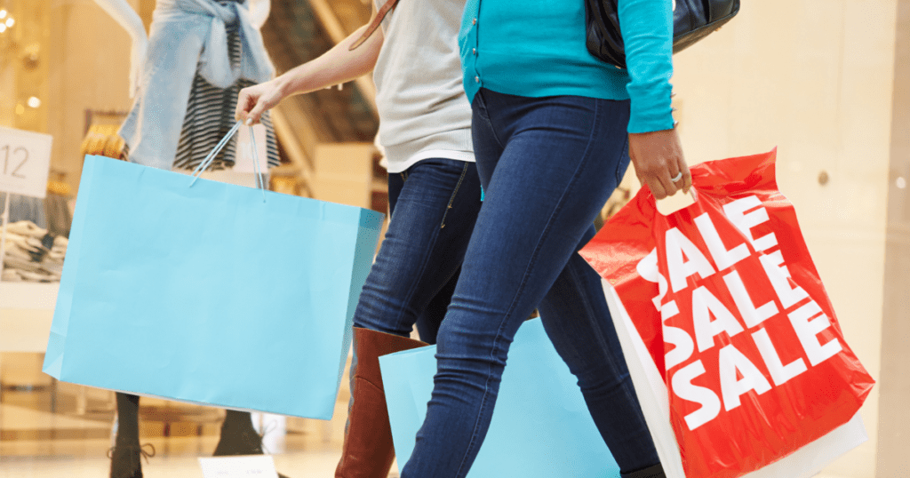 People strolling with shopping bags, one bag boldly reads "SALE," embracing the season of smart buying decisions.