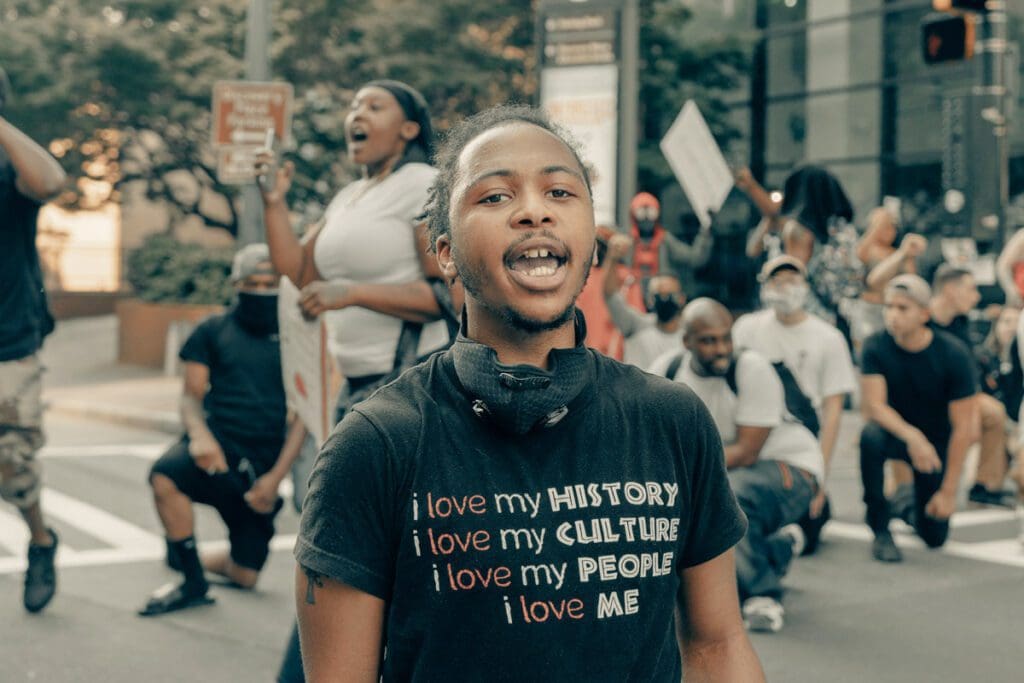 Leading the protest, the person communicates a powerful message with others kneeling in solidarity. This gathering provides an opportunity to talk about race and its impact on our society.