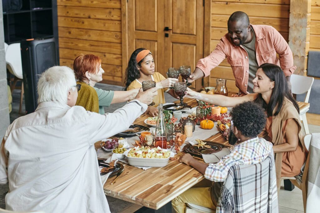 A group of people joyously toasting at a festive dinner table, engaged in meaningful communication on race, adding depth and unity to their celebration.