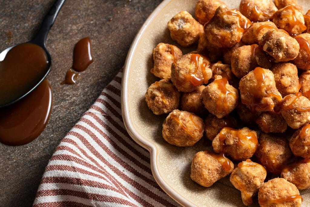 Caramel-covered popcorn chicken on a plate with festive sauce and a striped napkin nearby, reminiscent of Christmas treats.