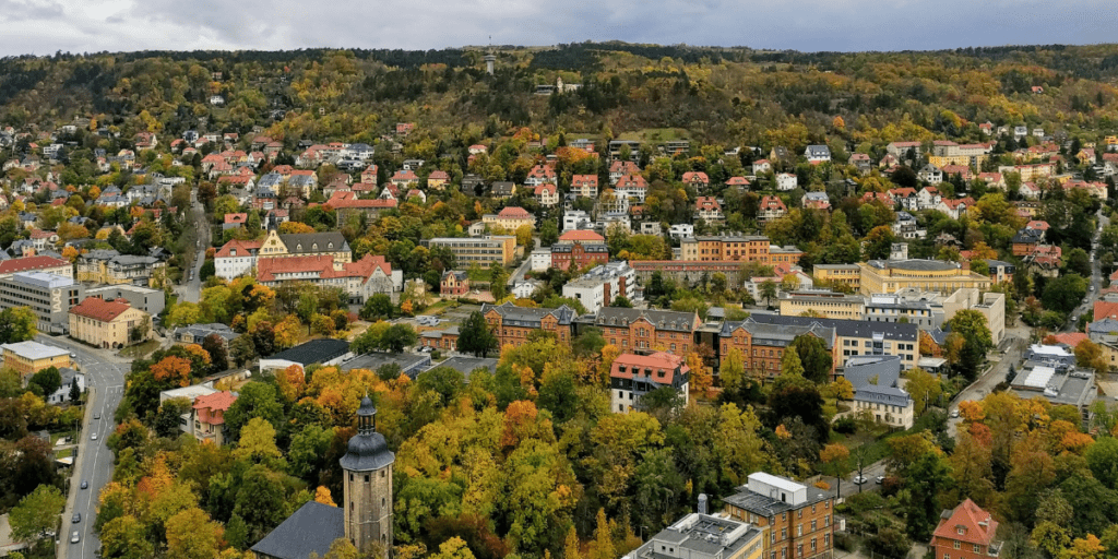 Aerial view of a town with colorful autumn trees and communal living spaces in the background.