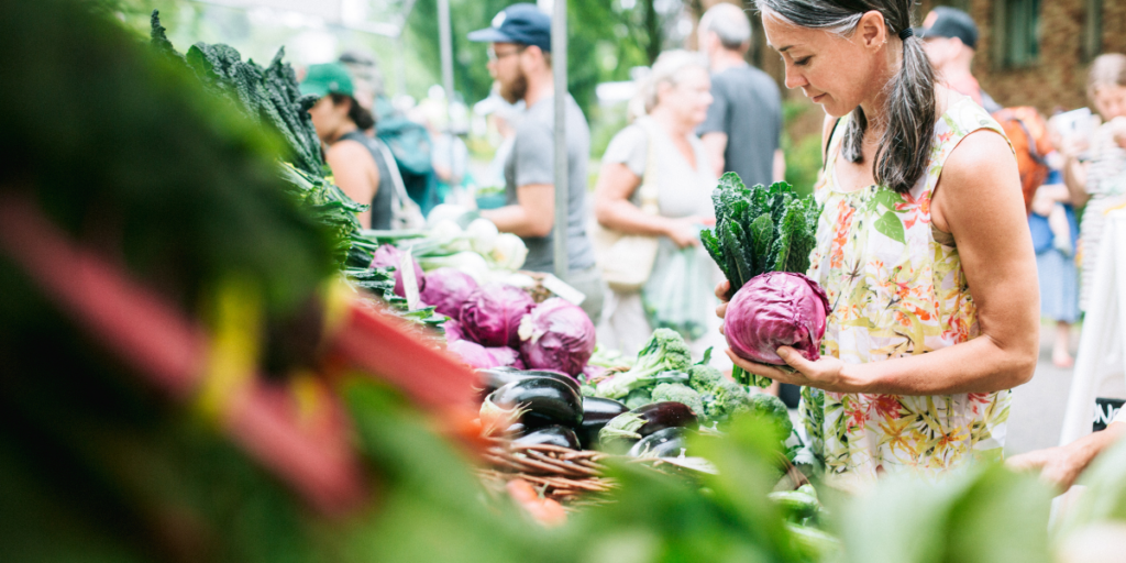 Woman choosing vegetables at a farmers market for her sustainable food plan.