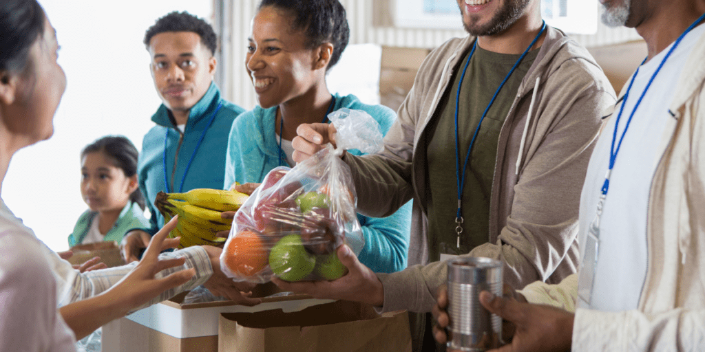 People ensuring food security at a 2025 community event, distributing fruit and canned goods.