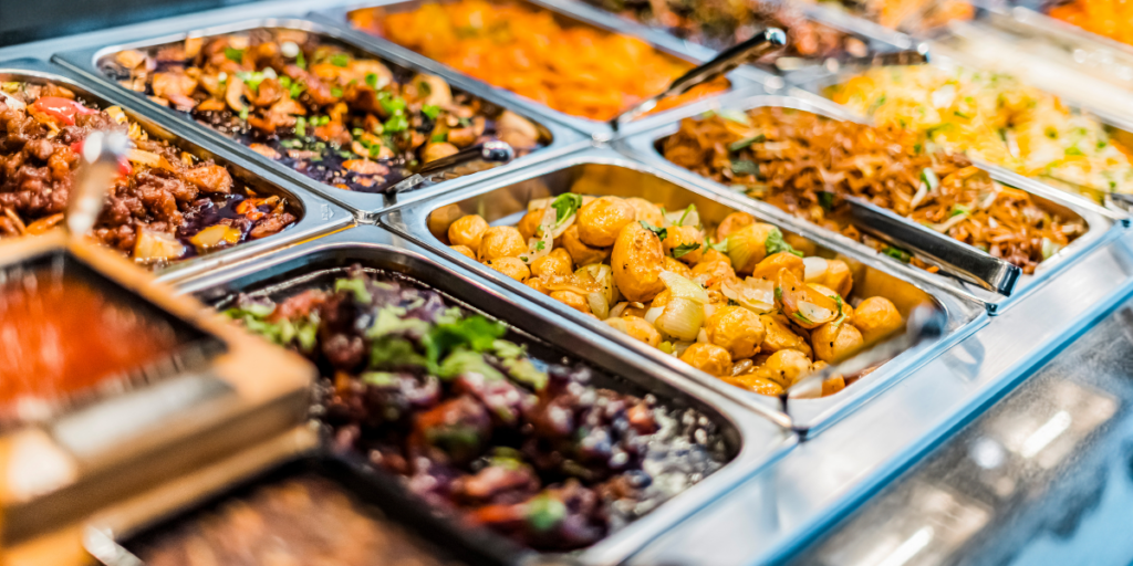 Buffet with potatoes, noodles, and veggies in stainless trays ensuring 2025 food security.