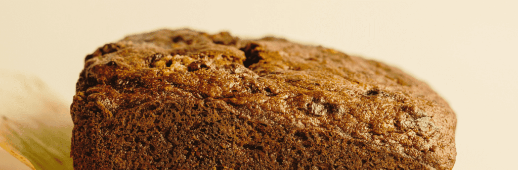Close-up of a slice of rich, dark brown bread with hints of foraged ingredients.