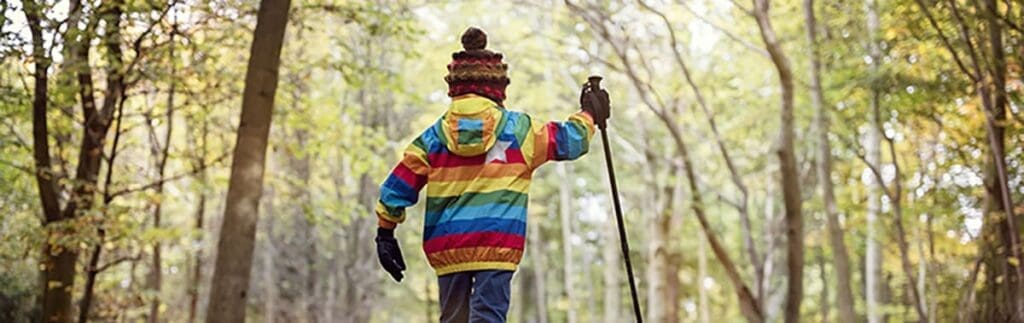 Child in a colorful jacket explores the autumn forest, enjoying fun activities for kids.