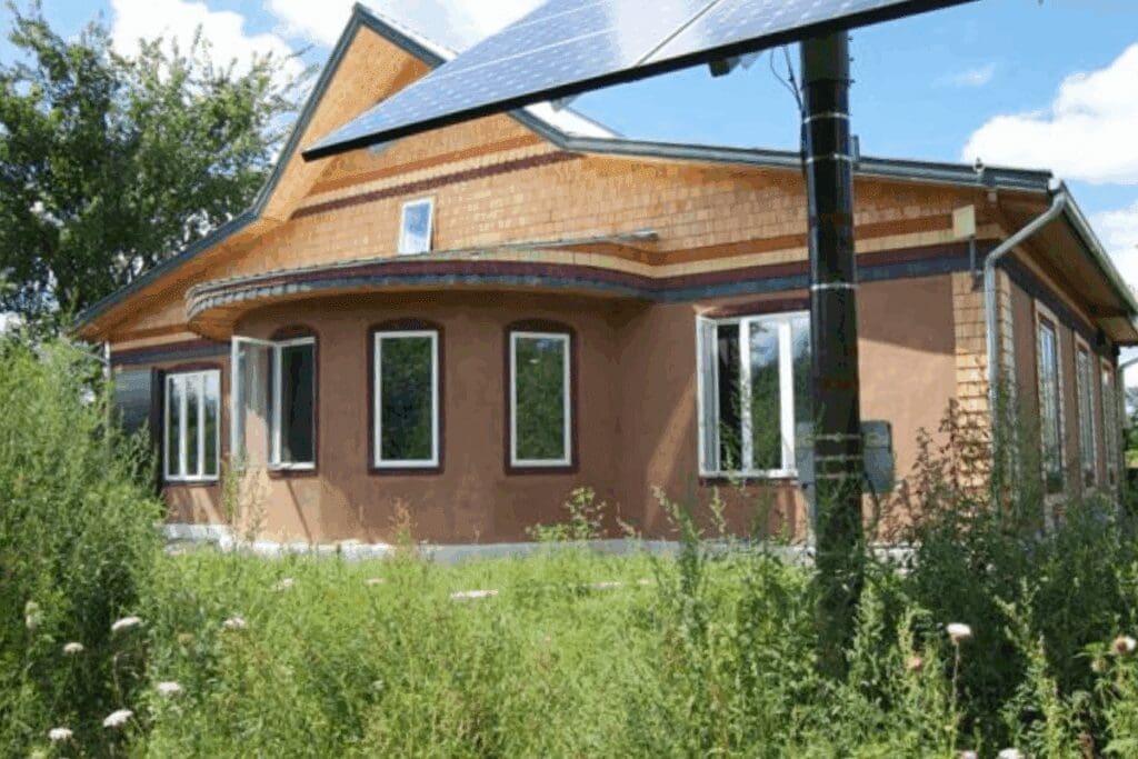 A hempcrete home with solar panels under a partly cloudy sky.