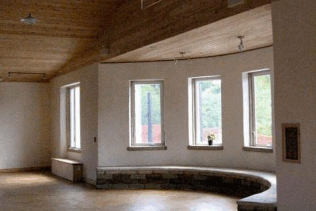 Curved stone bench under four windows; ideal for eco-friendly hempcrete construction projects.