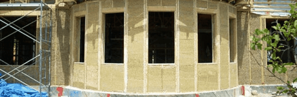 Partially constructed building showcases hempcrete insulation and multiple exposed window openings.