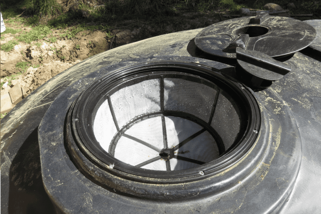 Close-up of an open water tank lid showing a mesh filter inside the tank.